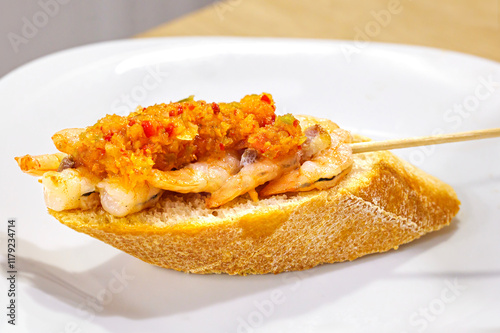 Traditional pintxo from San Sebastian: Grilled prawn tails served on bread and topped with a vinaigrette of red pepper, green pepper, and chive. photo