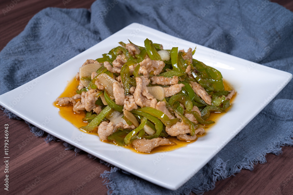 Shredded pork with green pepper on a white plate on the table Shredded pork with green pepper on a white plate on the table