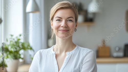 Free Download Portrait of a smiling woman in a white shirt, standing in a bright kitchen. - GFXLoad