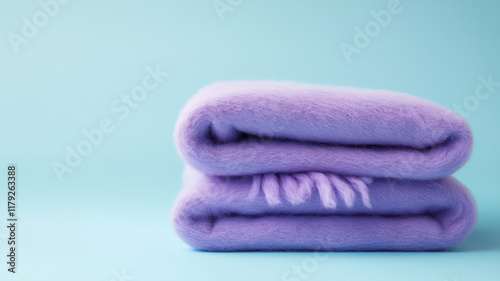 A purple blanket with a fringe is laying on a blue surface