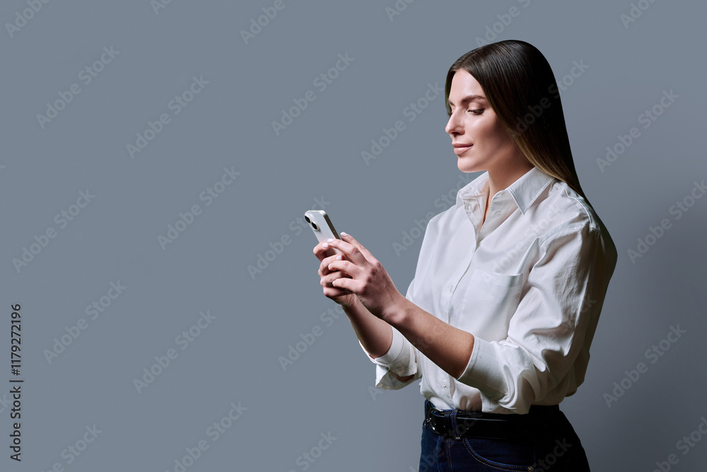 Profile view, young beautiful woman using mobile phone on grey background Profile view, young beautiful woman using mobile phone on grey background