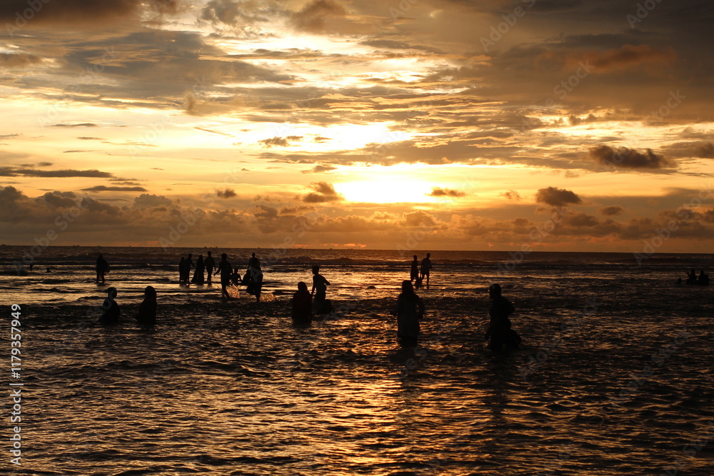 Silhouette people man a woman on the sunset background, mSunset on the tropical beach Seminyak. The tourists watching for beautiful sunset in the sea. Coast of the sea at colorful sunset. Silhouette people man a woman on the sunset background, mSunset on the tropical beach Seminyak. The tourists watching for beautiful sunset in the sea. Coast of the sea at colorful sunset.
