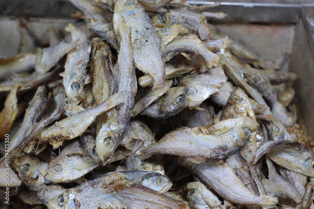 Crispy small fish placed on the stall for sale. Close up of stacked dried anchovies. A pile of dried anchovies displayed in a fish market, Little dried fish in an Asian fish market. Crispy small fish placed on the stall for sale. Close up of stacked dried anchovies. A pile of dried anchovies displayed in a fish market, Little dried fish in an Asian fish market.
