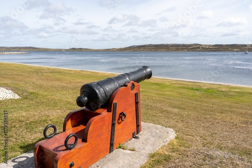 Historic cannon overlooking a tranquil bay.