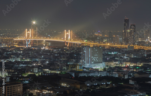 Obraz na płótnie Nightscape view of Skyscrapers with Thotsamarachan Bridge (Rama IX Bridge) crossing Chao phraya river. Beautiful city of Bangkok with bright glowing lights, use it as your Wallpaper, Poster and Space. w salonie