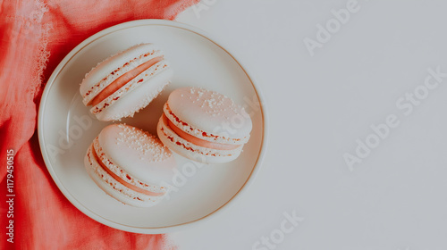 Delicate pink macarons on plate, coral fabric background, overhead shot, food blog use. photo