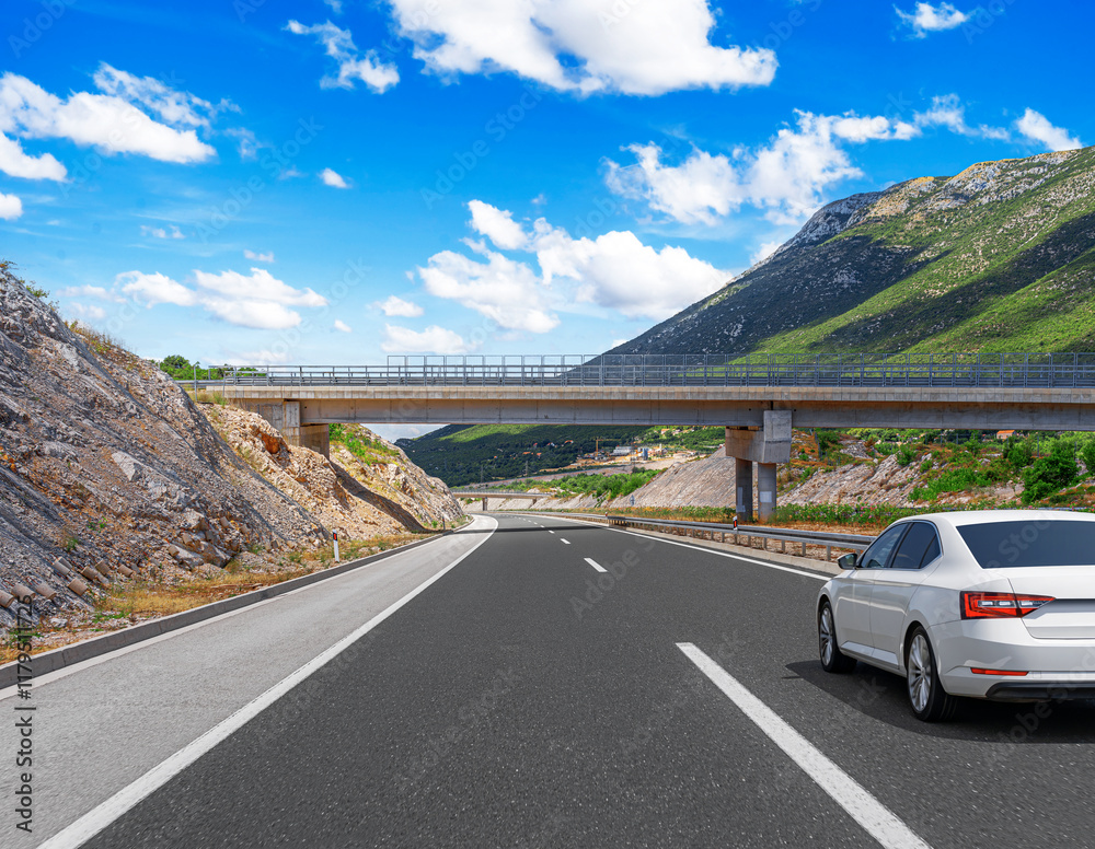 The car is driving along the highway surrounded by picturesque nature.