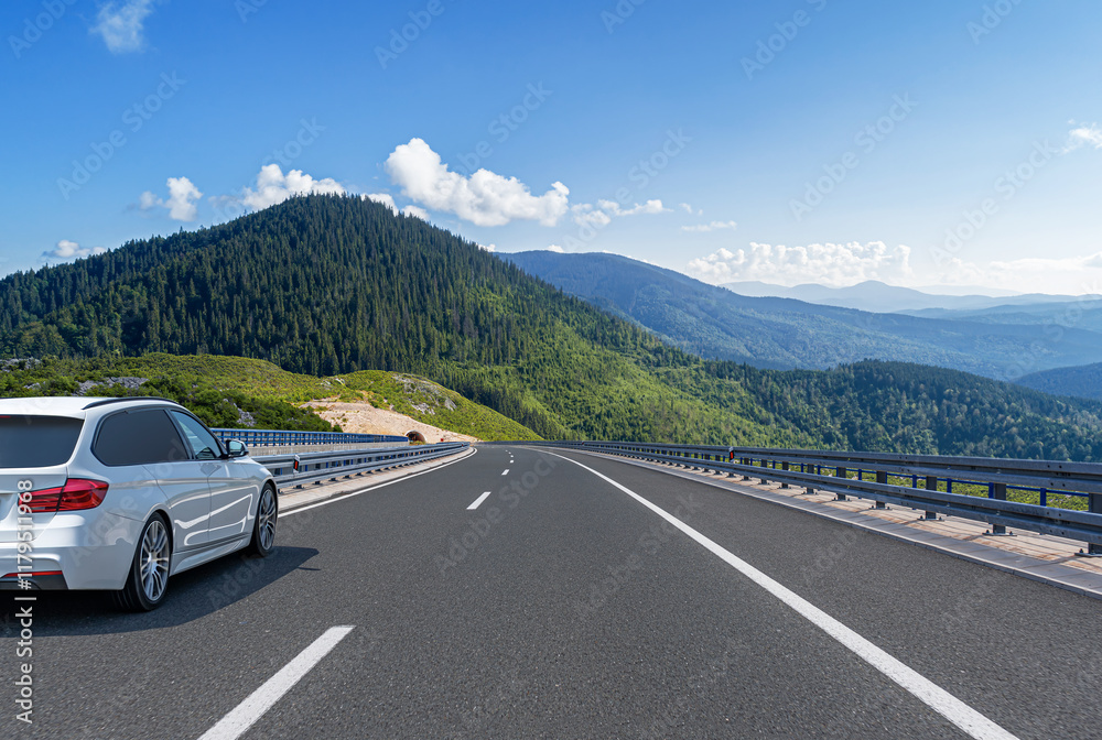 The car is driving along the highway surrounded by picturesque nature.