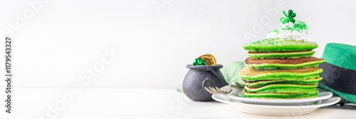 Green shamrock color pancakes with whipped cream and sugar sprinkles, for St Patrick`s day breakfast on lunch, with patricks holiday decorations on kitchen table photo