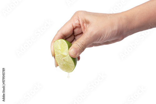 Hand squeeze lime with lime juice dripping on white