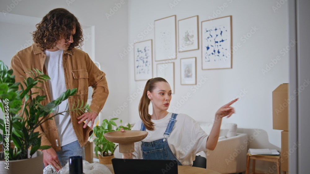 Couple discussing decor ideas while unpacking items in modern home. Woman laptop Couple discussing decor ideas while unpacking items in modern home. Woman laptop