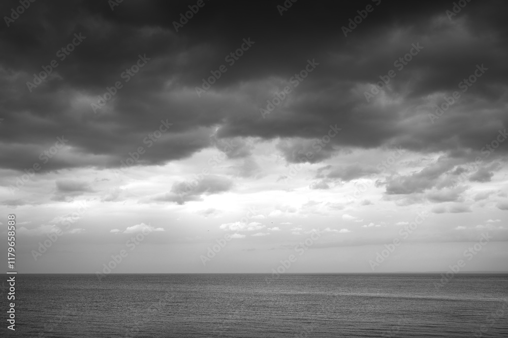 Obraz premium Simple black and white and dramatic view of Lake Superior with a menacing cloudy sky and calm water. Simple landscape background