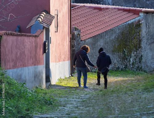 Two senior woman walking along street in medieval villahe in italy photo