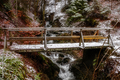 Winter im Wald mit Brücke und Bachlauf