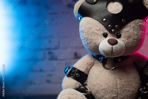 Cute teddy bear in leather belt belt and handcuffs Accessories for BDSM games in neon background light