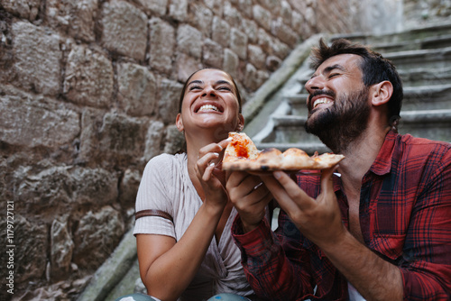 Couple eating pizza at stairs