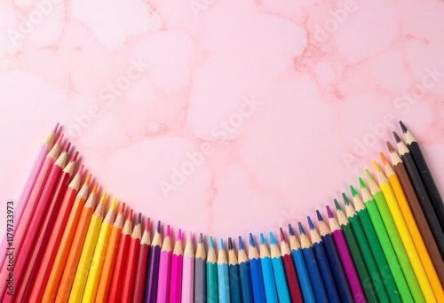 Colored pencils in semi circle on pink marble background photo