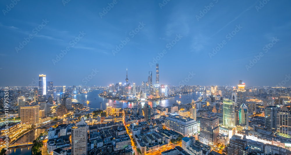 Aerial view of a modern city skyline with a river at night, showcasing illuminated buildings and skyscrapers Aerial view of a modern city skyline with a river at night, showcasing illuminated buildings and skyscrapers