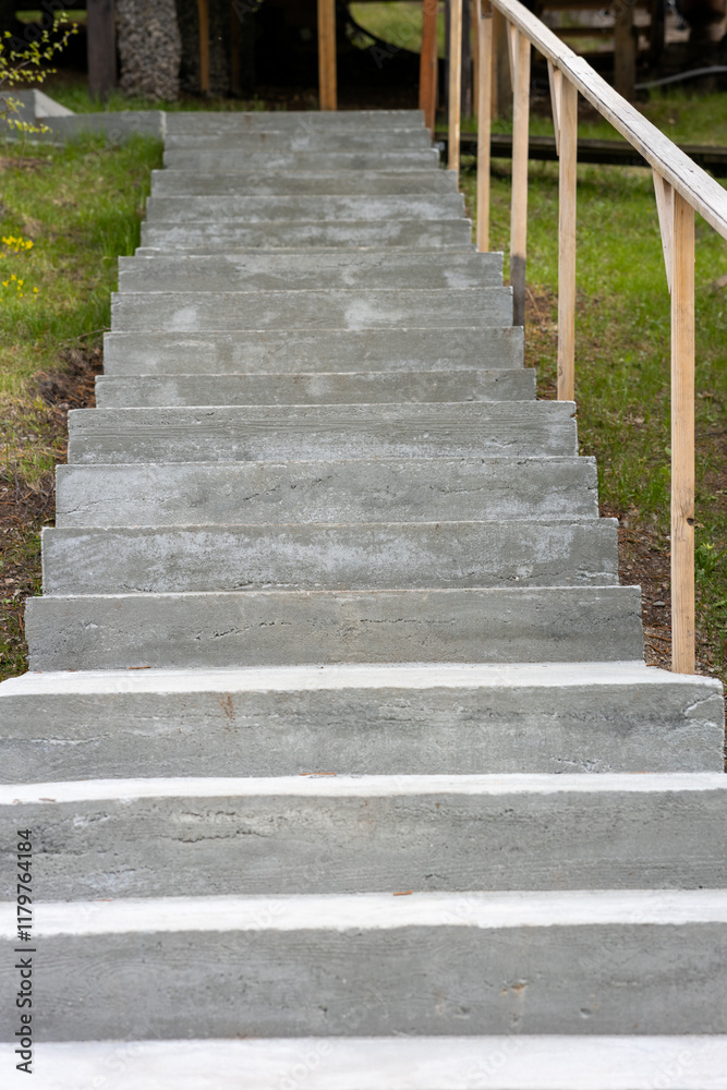 A concrete staircase with a wooden railing A concrete staircase with a wooden railing