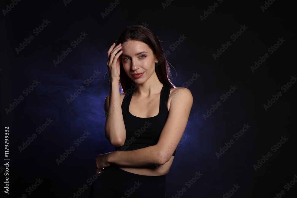 Beautiful woman in stylish sportswear on dark background with color light and smoke Beautiful woman in stylish sportswear on dark background with color light and smoke