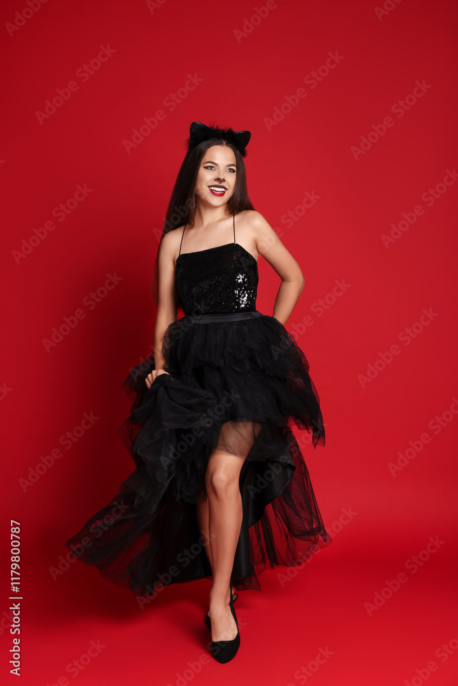 Woman with cat makeup and ears in beautiful dress on red background Woman with cat makeup and ears in beautiful dress on red background