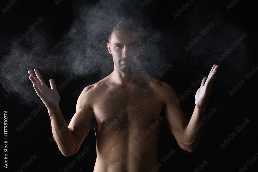 Obraz premium Man clapping hands with talcum powder before training on black background