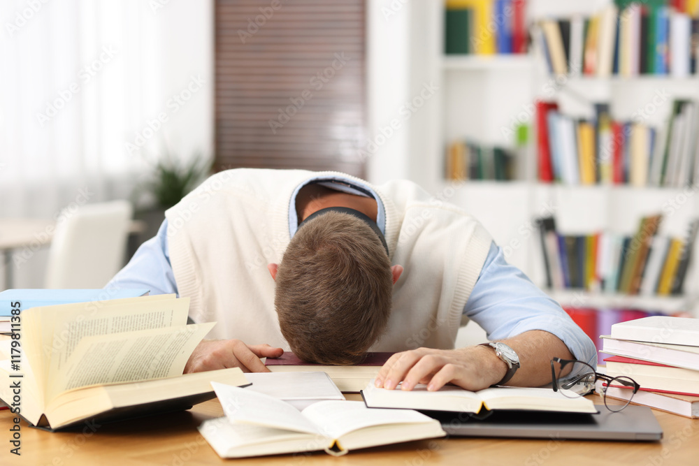 Preparing for exam. Tired student sleeping among books at table indoors Preparing for exam. Tired student sleeping among books at table indoors