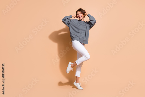 Full body photo of attractive young woman enjoy music dancer wear trendy gray outfit isolated on beige color background photo