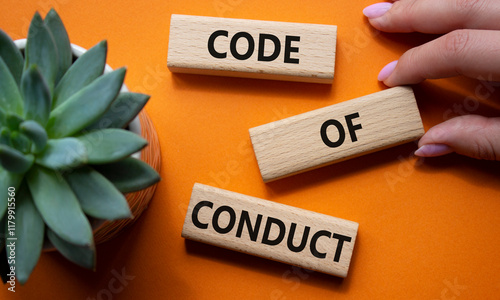 Code of conduct symbol. Wooden blocks with words Code of conduct. Businessman hand. Beautiful orange background with succulent plant. Business and Code of conduct concept. Copy space.