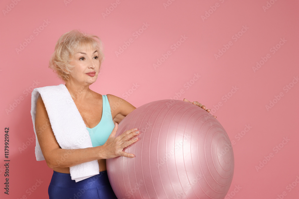 Senior woman with towel and fitness ball on pink background. Space for text Senior woman with towel and fitness ball on pink background. Space for text