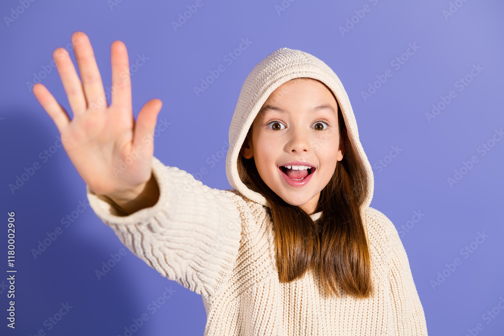 Excited young girl in a cozy white sweater showing hand gesture on a vibrant purple background. Excited young girl in a cozy white sweater showing hand gesture on a vibrant purple background.
