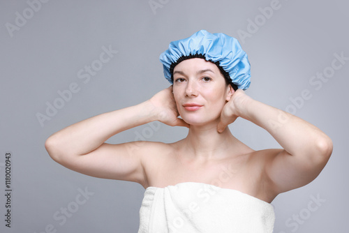 Woman wearing shower cap on grey background