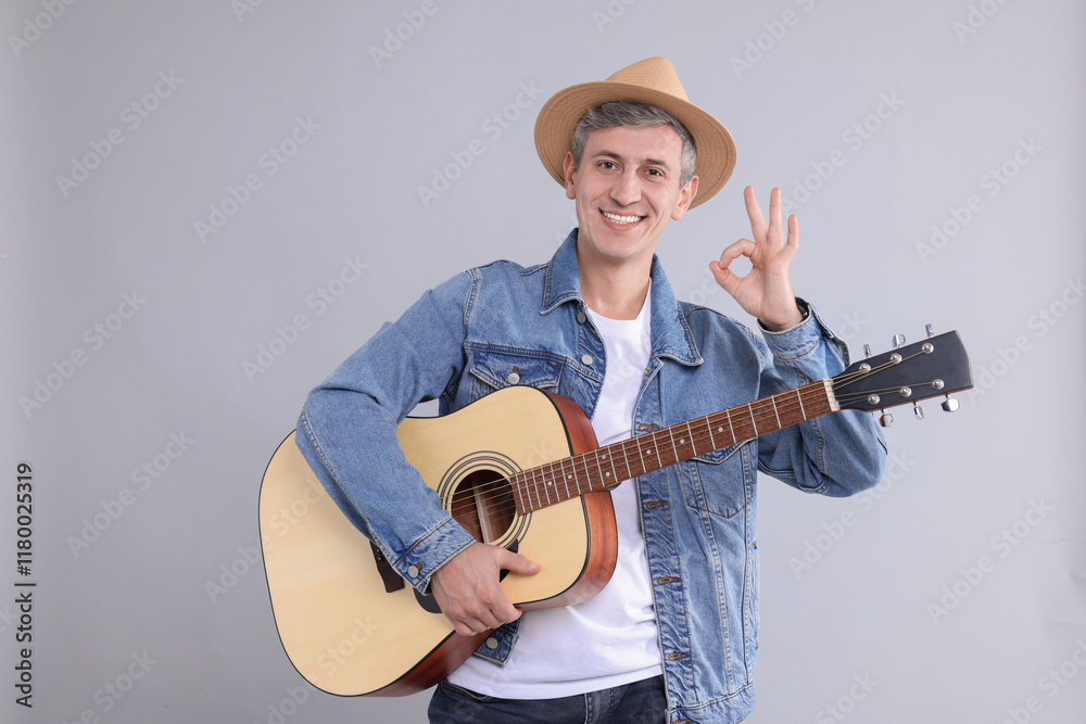 Happy man with guitar showing okay gesture on light grey background Happy man with guitar showing okay gesture on light grey background