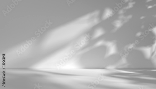 Light grey background image for product presentation, white wall with light casting shadow of leaves on it. Image to represent sense of nature touch, or natural ingredients.