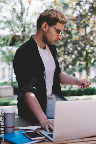 Konstfotografi Adult dedicated employee revising reports and interacting with laptop on street