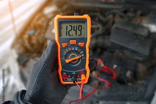 Obraz na płótnie Man using multimeter to measure car battery voltage level during winter maintenance, alternator producing 12.49 volts with engine idling, bad alternator. Alternator malfunction w salonie