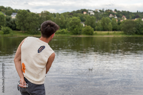 Junger Mann aus Indien steht am Fluss und wirft Steine ins Wasser photo