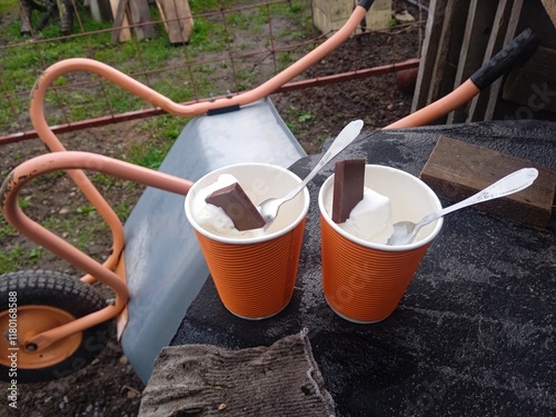 ice cream in a cardboard cup with a piece of chocolate on the table outside