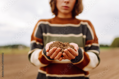 Women's hands sort through black soil in the field. Farmer is checking soil quality before sowing. Ecology, agriculture concept. photo