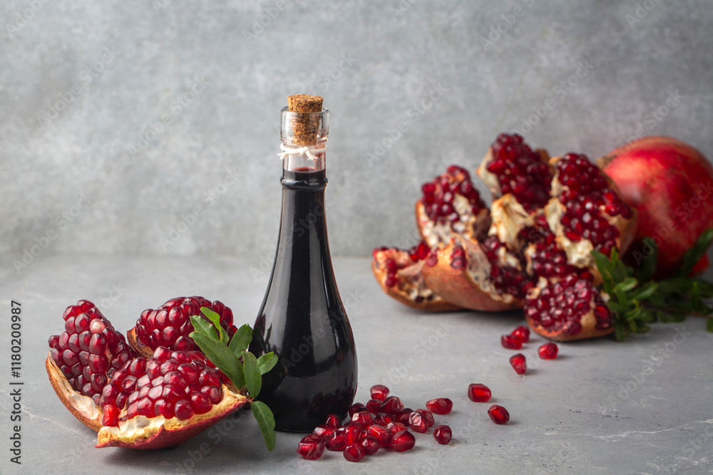 Glass bottle of pomegranate sour sauce with fresh ripe whole and split pomegranate fruit (Turkish name; nar eksisi)