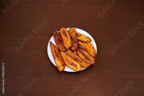 Fried plantain bananas on wooden background. Traditional African recipe cuisine