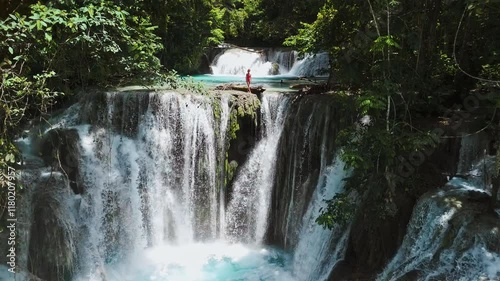 Cascade waterfalls and traveller woman staying on rock, drone view photo