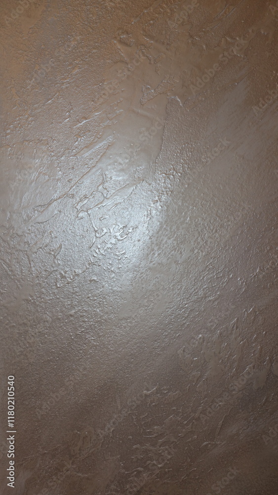 Fototapeta premium Close-up of a textured beige plaster wall with subtle sheen.