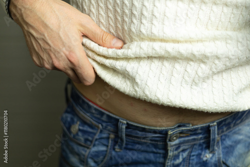 man lifts the hem of his sweater