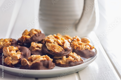 Photography of chocolate Florentines cookies with almonds and chocolate on plate on white table. photo