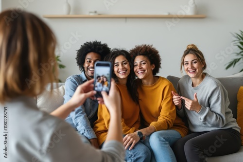 Woman taking a selfie with cellphone to cheerful female friends sitting on couch in living room photo