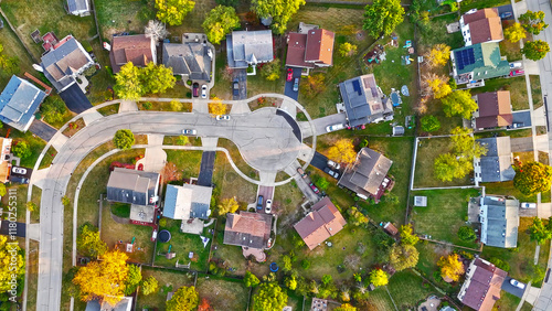 Aerial View of Suburban Cul-de-Sac Neighborhood. Top-down aerial shot of a suburban cul-de-sac surrounded by homes, driveways, and vibrant green yards in a peaceful neighborhood.