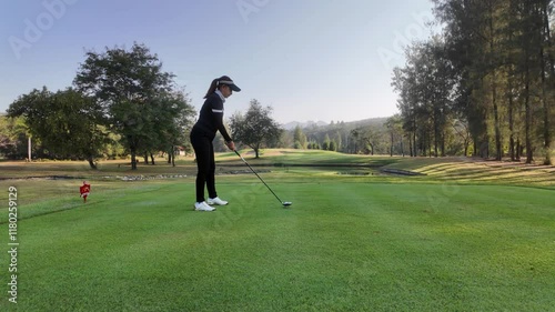 Woman playing golf on beautiful course , swinging and hitting golf ball , luxury vacation