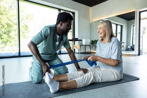 Wall Mural Man physiotherapist guiding woman through leg exercise with resistance band for