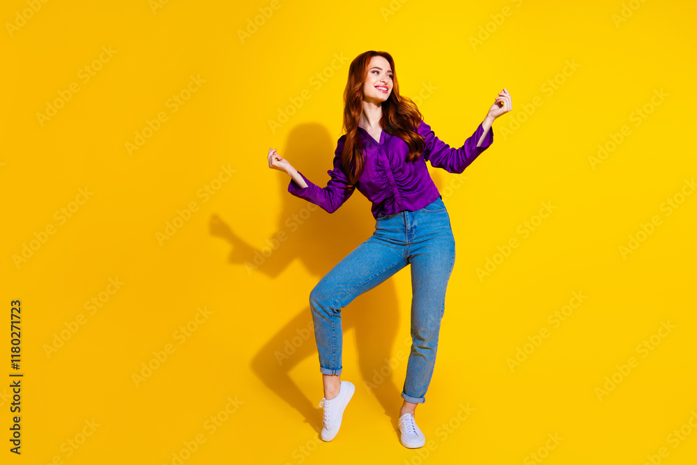 Fototapeta premium Photo portrait of beautiful young red hair curls lady in violet shirt and jeans dancing model isolated on yellow color background
